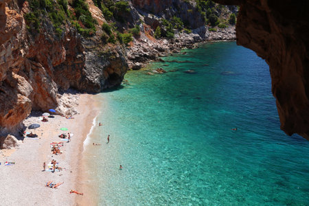 KONAVLE, CROATIA - JUNE 28, 2019: People spend vacation at Pasjaca beach below cliffs in Konavle region of Dalmatia, Croatia.のeditorial素材