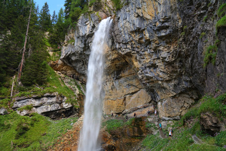 OBERTAUERN, AUSTRIA - AUGUST 5, 2022: People walk the trail beneath Johannes Waterfall in Tauern mountains in Austria. It is one of highest single drop waterfalls in Austria.のeditorial素材