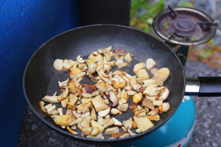 Norway outdoor breakfast - frying fresh bolete mushroom on a pan in campsite.の写真素材