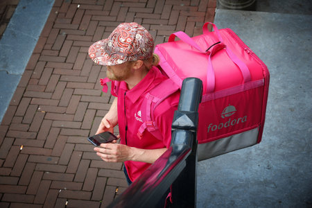 AMSTERDAM, NETHERLANDS - JULY 9, 2017: Foodora app food couriers wait in Amsterdam, Netherlands. Bicycle food delivery is popular in Amsterdam.のeditorial素材