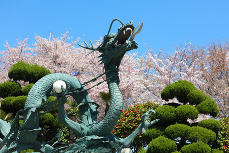 BUSAN, SOUTH KOREA - MARCH 27, 2023: Dragon statue with cherry blossoms in background in Yongdusan Park in Busan, South Korea.のeditorial素材