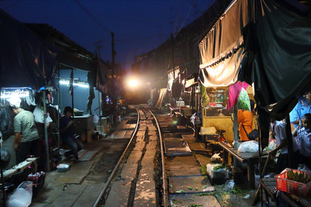 SAMUT SONGKRAM, THAILAND - DECEMBER 12, 2013: Train rides through Mae Klong market in Thailand. The market is notable for its location on active railroad line.のeditorial素材