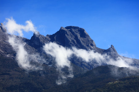 Mount Kinabalu on a sunny day. King Edward's Peak surrounded by clouds. Highest mountain in Malaysia. Sabah region of Borneo.の写真素材