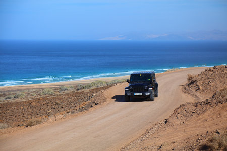 FUERTEVENTURA, SPAIN - DECEMBER 7, 2024: Jeep Wrangler 4x4 car drives the mountain gravel road to famous Cofete beach in Fuerteventura island of Canary Islands, Spain.のeditorial素材
