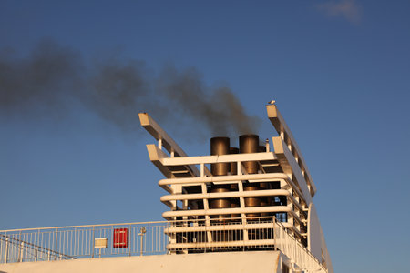 Black exhaust fumes smoke from a ferry chimney in Denmark. Air pollution from maritime transportation.の写真素材