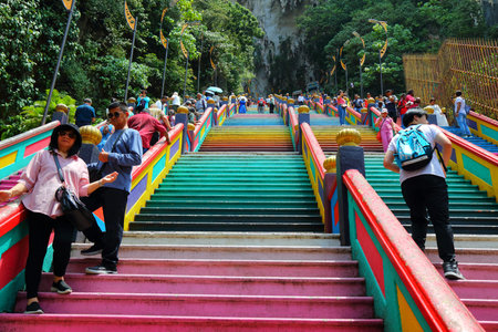 BATU CAVES, MALAYSIA - MARCH 17, 2024: Pilgrims climb the stairs to Batu Caves temple complex in the outskirts of Kuala Lumpur. Batu Caves is on of most recognized Hindu religion centres outside India.のeditorial素材