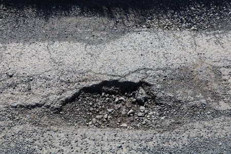 Pothole damage asphalt road surface in Northern Ireland, UK. Countryside road maintenance concept.
