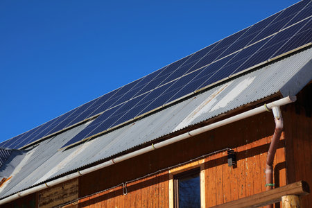 Rural home retrofitted with photovoltaic panels in Poland. Rooftop solar panels on a mountain home.の写真素材