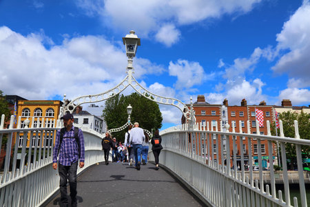 DUBLIN, IRELAND - JULY 6, 2024: People visit Ha'penny Bridge, landmark in Dublin, Ireland. Cast iron pedestrian bridge over River Liffey in Dublin.のeditorial素材
