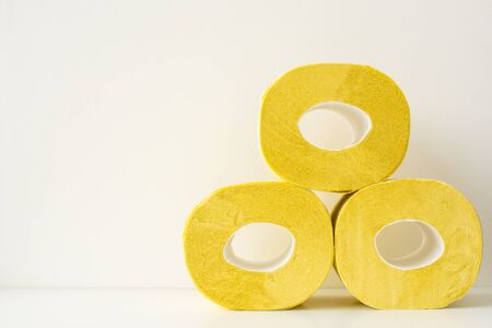 Three yellow color toilet paper rolls on white backgroundの写真素材