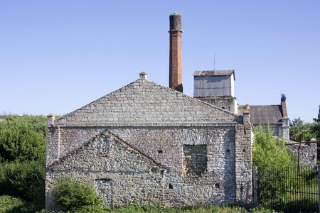 An abandoned building of an old 19th century factory with a long brick smokestack tower.の写真素材