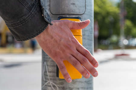 Close up of an adult male hand is pressing button or giving touchless stop signal for pedestrian crossingの写真素材