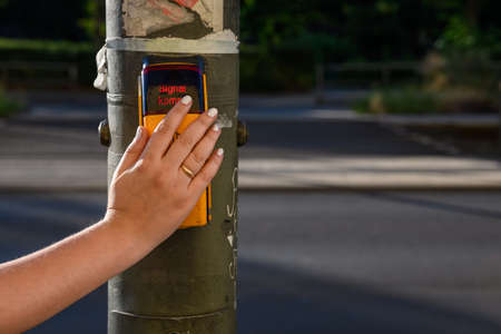 Close up of an adult female hand is giving touchless stop signal for pedestrian crossing in Germanyの素材 [FY310151581206]