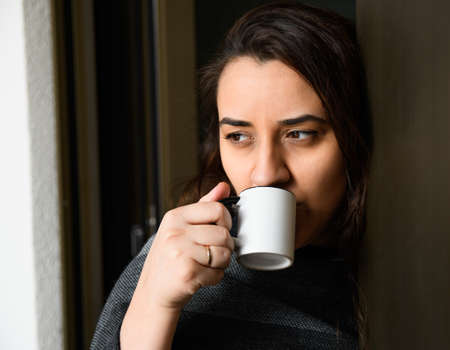 Young woman holding a cup of coffee while looking awayの写真素材