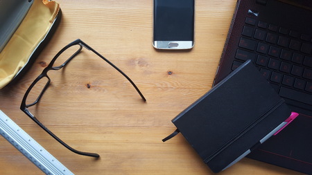 Office desk table with glasses, laptop, phone, notebook and rulerの写真素材