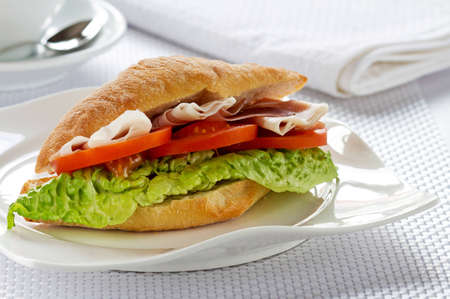 Sandwich with ham, cheese, tomatoes, and lettuce on a plate の写真素材
