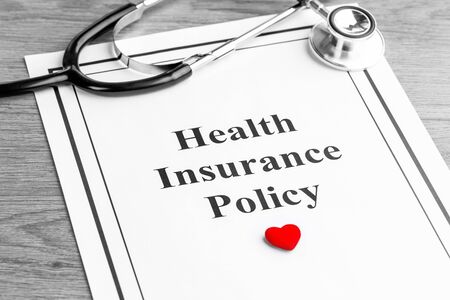 Insurance policy. Medical stethoscope, policy and red heart on table. Business and medical background conceptの写真素材