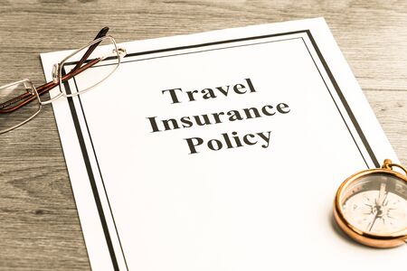 Travel insurance policy with glasses and compass on table. Business concept