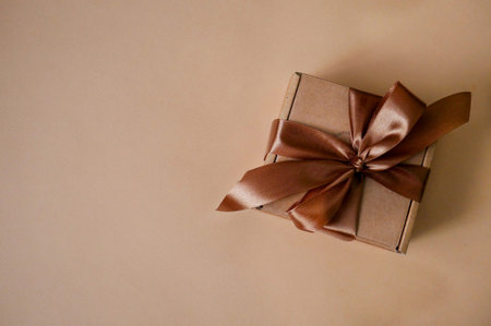 Brown gift box with a bow on a beige background
