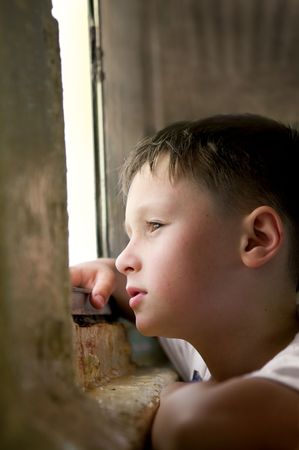 Thoughtful boy at a window の写真素材