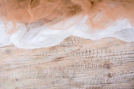 Lightweight fabric mesh lace on textured wooden table, texture of the fabric is beautifully draped backgroundの写真素材