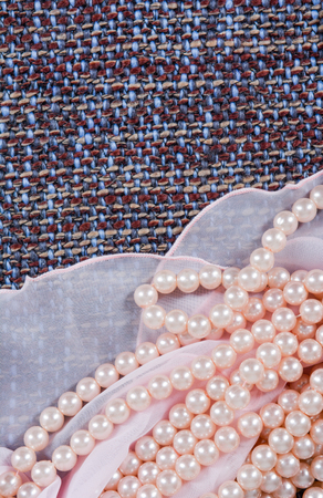 Beads made from artificial pearls on the beautiful fabric. Contrast of textures. Rough and light fabric with pearlsの写真素材
