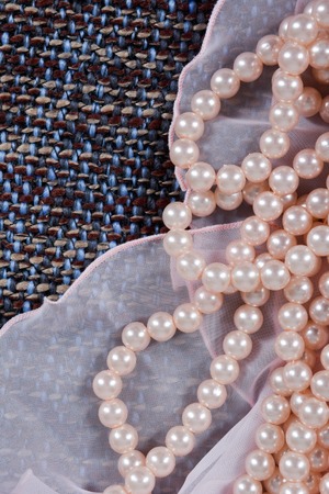Beads made from artificial pearls on the beautiful fabric. Contrast of textures. Rough and light fabric with pearlsの写真素材