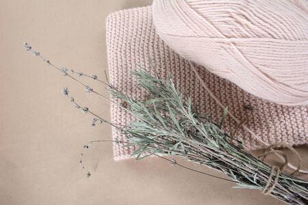 Coil of wool yarn for knitting, a beige scarf and a bunch of dried lavender
