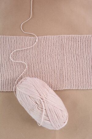 Hobby. Knitting. A skein of wool and a knitted scarf of beige thread.