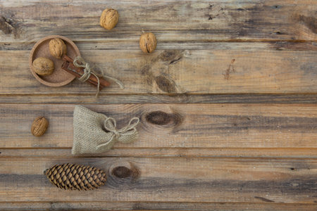 Walnuts, a bag, cinnamon and a fir cone on the background of old wooden boards.の写真素材