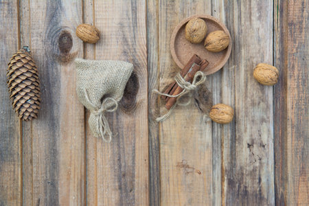 Walnuts, a bag, cinnamon and a fir cone on the background of old wooden boards.の写真素材