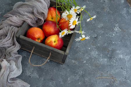 Bouquet of wild flowers chamomile with fruits of nectarines in a wooden boxの写真素材