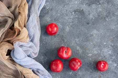 Top view of fresh organic ripe plums on the table decorated with grey gauze fabric, copy space. Flat lay.の写真素材