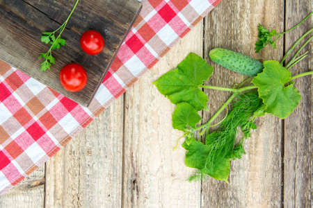 Fresh vegetables with leaves, checkered tablecloth on a wooden table. Rustic style. Copy spaceの写真素材