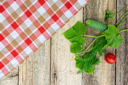 Fresh vegetables with leaves, checkered tablecloth on a wooden table. Rustic style. Copy spaceの写真素材