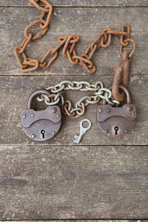 Two old rusty padlock and rusty chain on wooden background. The concept of a couple relationship