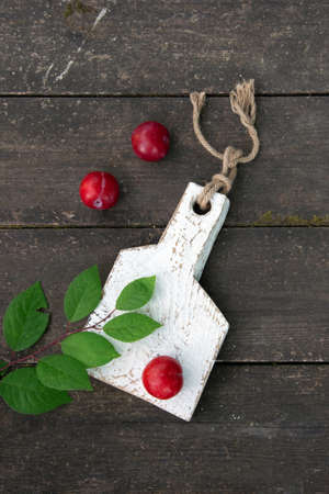 Fresh plums with leaves on the wooden table close-up. Copy space