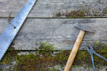 Vintage hand-made tools on wooden background of old planks covered with moss. Rustic style photo