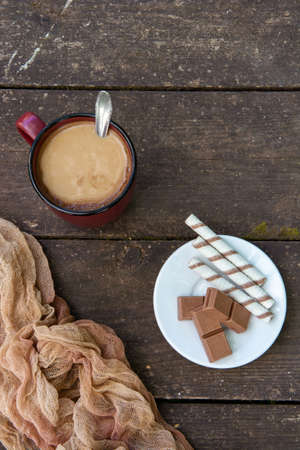 A cup of coffee, pieces of chocolate bars and sticks against a wooden table. Dessert. Copy spaceの写真素材