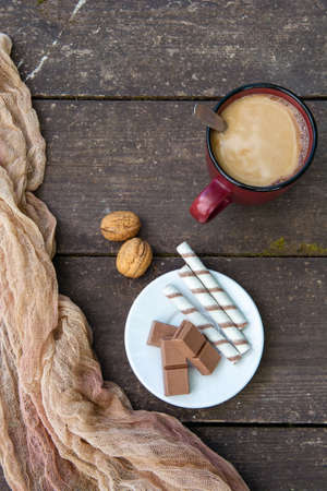 A cup of coffee, pieces of chocolate bars and sticks against a wooden table. Dessert. Copy spaceの写真素材