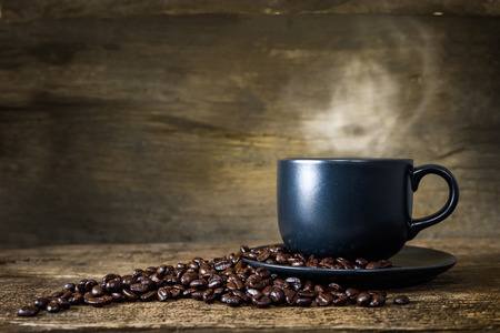 Cup of hot coffee and coffee beans on old wood backgroundの写真素材