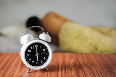 Man sleeping with alarm clock in foregroundの写真素材