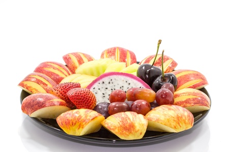 beautiful and delicious fresh mix fruits in black plate isolated on white backgroundの写真素材