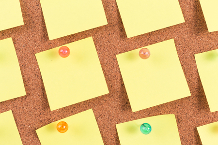yellow reminder sticky note on cork board, empty space for textの写真素材