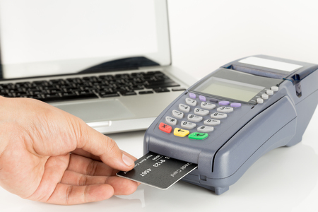 Hand Swiping Credit Card With Laptop In Backgroundの写真素材