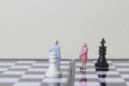 Simple illustration for photo War, Battle or politic situation concept, 2 standing mini figure, man and woman negoitation or debate beyond Small Magnetic Plastic chessの写真素材