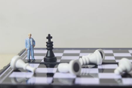 Simple illustration photo concept, 1 standing businessman mini figure toy help to winning war or Battle Small Magnetic Plastic chess Kingの写真素材