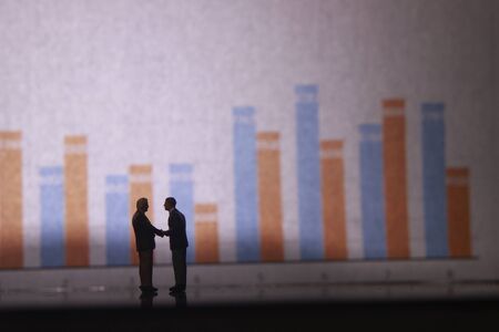 Simple Illustration Photo for Silhouette Two Man Handshaking for Business Agreement with graphic Chart as a backgroundの写真素材
