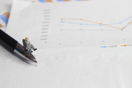 Simple Illustration Photo 1 Sitting Mini Figure old man Toy Reading Graphic Business Chart at Black and stainless steel penの写真素材