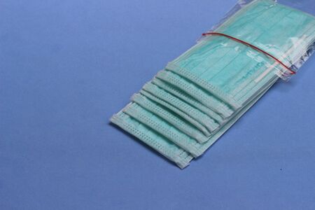 Photo, Light Green Surgical mask at blue background for prevention from covid-19 and other virus or...